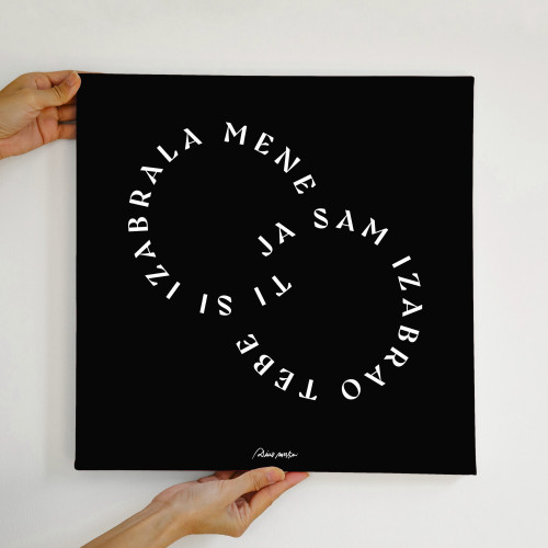 Crni dekorativni poster sa bijelim slovima "Ti si izabrala mene, ja sam izabrao tebe" iz pjesme "Zauvijek ovako u rukama osobe na bijeloj pozadini.