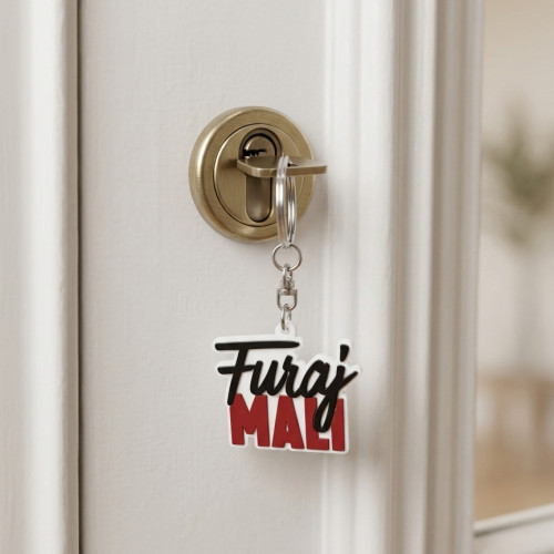 Gumeni privjesak za ključeve "Furaj mali" s crno - crvenim slovima na cvjetnoj pozadini.