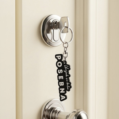 Crni gumeni privjesak s reljefnim bijelim natpisom "Uvijek si bila posebna", nježno postavljen među &scaron;areno cvijeće.